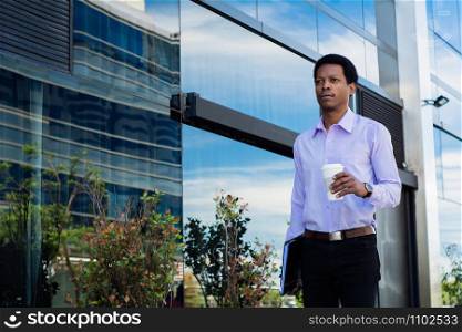 Portrait of young latin businessman holding coffee cup outside of office.