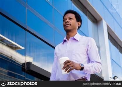 Portrait of young latin businessman holding coffee cup outside of office.