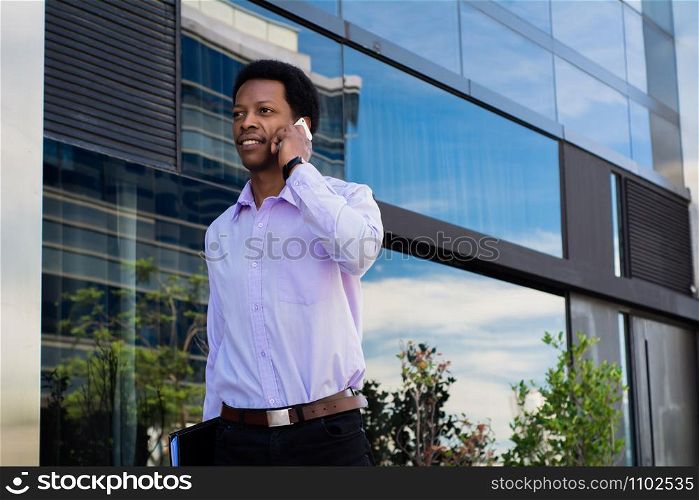 Portrait of young latin businessman talking on mobile phone in the city.