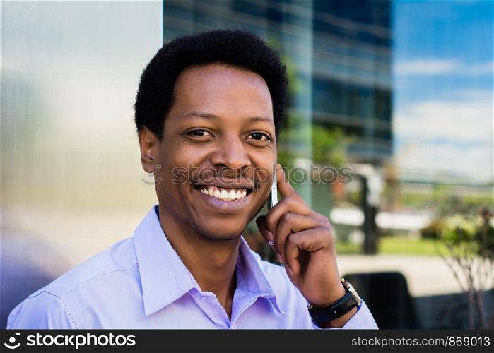 Portrait of young latin businessman talking on mobile phone in the city.