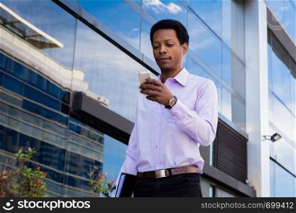 Portrait of young latin businessman using mobile phone in the city.