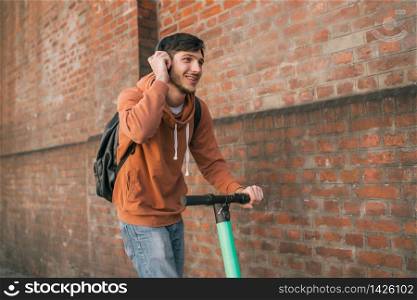 Portrait of young latin man driving electric scooter on city street. Modern and ecological transportation concept.
