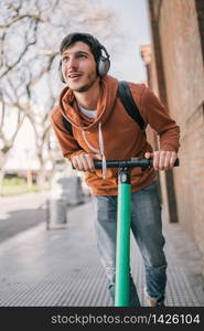 Portrait of young latin man driving electric scooter on city street. Modern and ecological transportation concept.