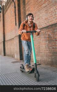 Portrait of young latin man driving electric scooter on city street. Modern and ecological transportation concept.