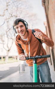 Portrait of young latin man driving electric scooter on city street. Modern and ecological transportation concept.