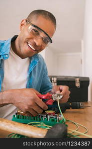 Portrait of young latin man fixing electricity problem with cables at new home. Repair and renovation home concept.