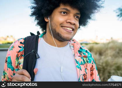 Portrait of young latin man holding a cup of coffee while walking outdoors on the street. Urban concept.