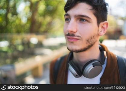 Portrait of young latin man listening to music with headphones outdoors in the street. Urban concept.
