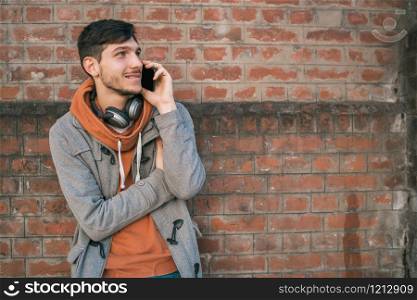 Portrait of young latin man talking on the phone outdoors in the street. Urban and communication concept.