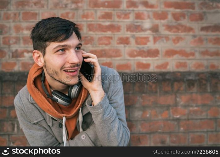 Portrait of young latin man talking on the phone outdoors in the street. Urban and communication concept.