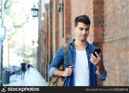 Portrait of young latin man typing on his phone. Outdoors.. Latin man typing on his phone.