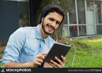 Portrait of young latin man using digital tablet in park . Outdoors.