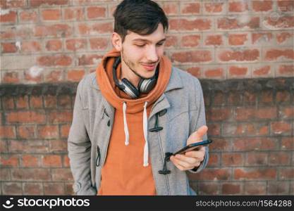 Portrait of young latin man using his mobile phone outdoors in the street. Communication concept.