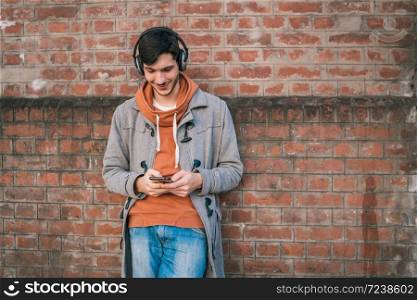 Portrait of young latin man using his mobile phone outdoors in the street. Communication concept.