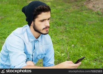 Portrait of young latin man using his smartphone. Outdoors.