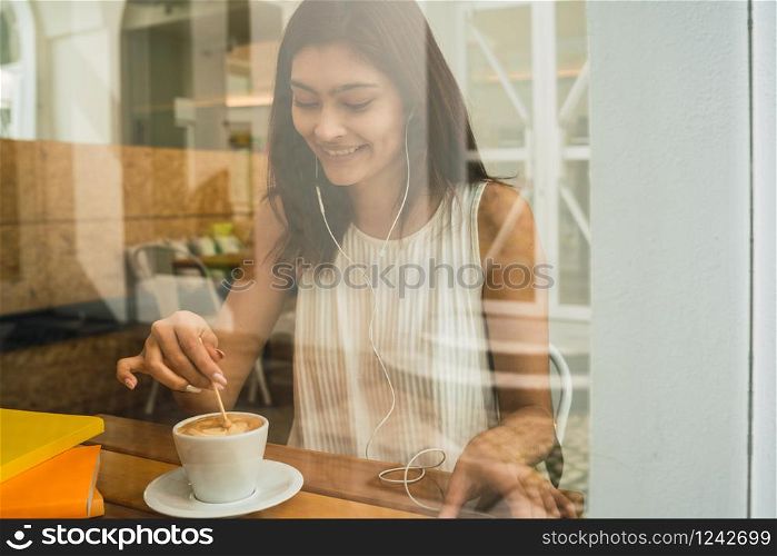 Portrait of young latin woman enjoying and drinking a cup of coffee at coffee shop. Lifestyle concept.