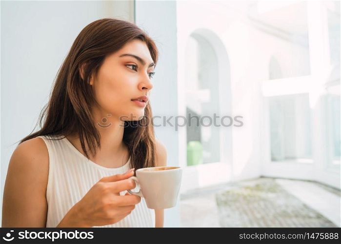 Portrait of young latin woman enjoying and drinking a cup of coffee at coffee shop. Lifestyle concept.