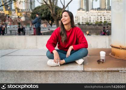 Portrait of young latin woman sitting outdoors with a cup of coffee. Urban concept.