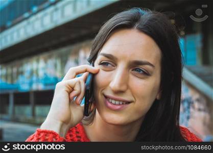Portrait of young latin woman talking on her mobile phone. Outdoors.
