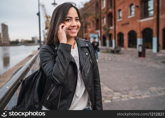 Portrait of young latin woman talking on the phone outdoors in the street. Urban concept.