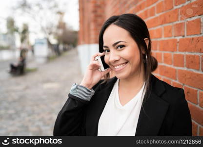 Portrait of young latin woman talking on the phone outdoors in the street. Urban concept.