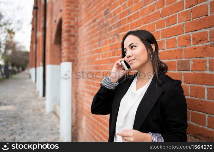 Portrait of young latin woman talking on the phone outdoors in the street. Urban concept.