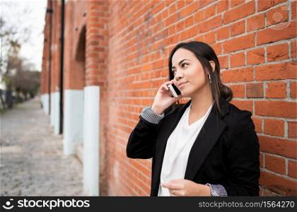 Portrait of young latin woman talking on the phone outdoors in the street. Urban concept.
