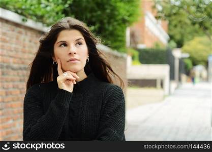 Portrait of young latin woman trying to remember. Woman thinking. Outdoors