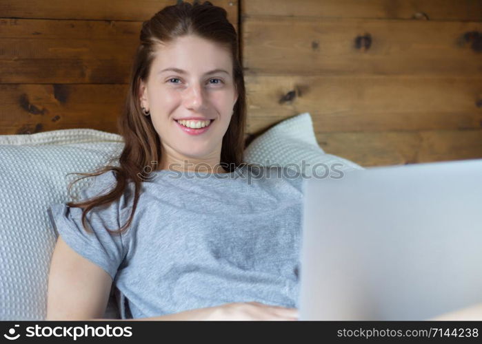 Portrait of young latin woman using her laptop while lying on the bed at home. Lifestyle concept