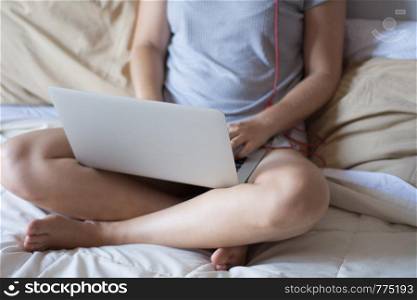 Portrait of young latin woman using her laptop while lying on the bed at home. Lifestyle concept