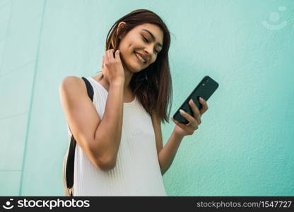 Portrait of young latin woman using her mobile phone outdoors in the street. Urban and communication concept.