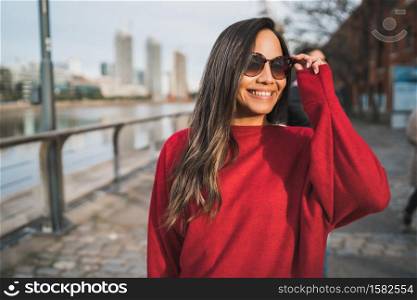 Portrait of young latin woman wearing sunglasses outdoors in the street. Urban concept.
