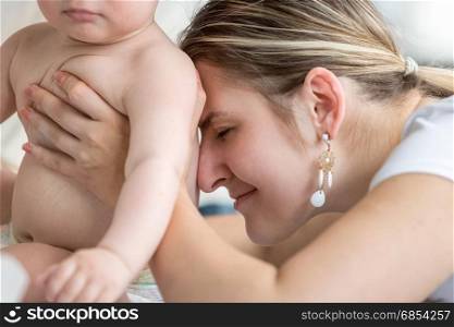 Portrait of young loving mother embracing her baby