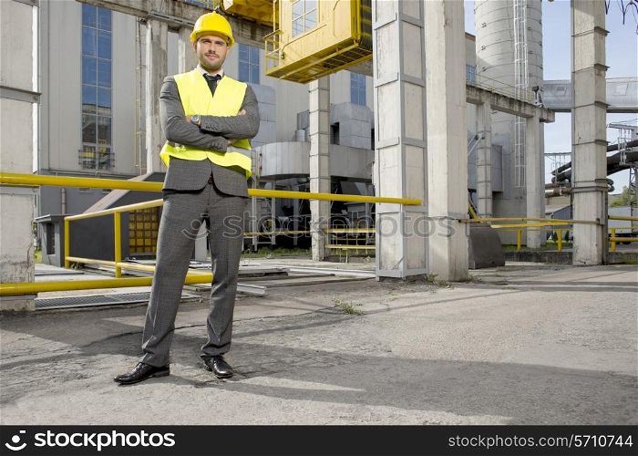 Portrait of young male architect standing arms crossed outside industry