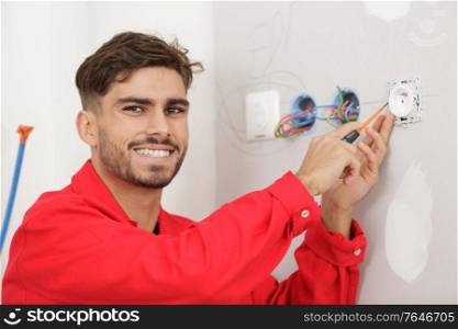 portrait of young male electrician wiring socket