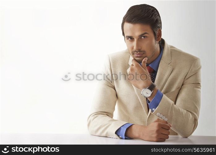 Portrait of young male entrepreneur sitting at office desk