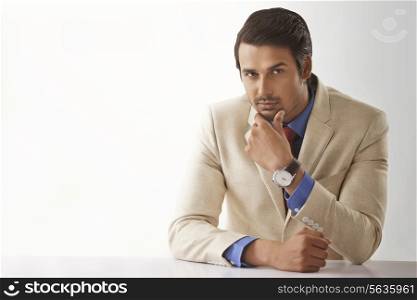 Portrait of young male entrepreneur sitting at office desk