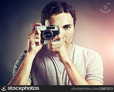 Portrait of young male photographer with a camera. Man shoots at camera