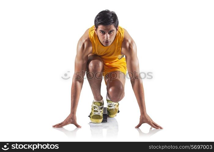 Portrait of young male runner at starting block isolated over white background