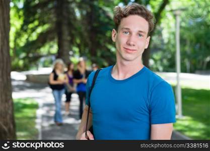 Portrait of young male smiling while his classmates walking in the background