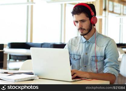 Portrait of Young male student using laptop and learning online in the university library.