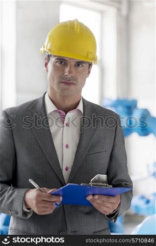 Portrait of young male supervisor holding clipboard in industry