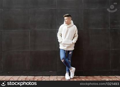 Portrait of young male with hands on pocket leaning on wall outdoors