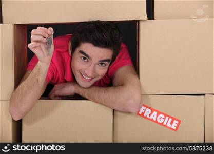 portrait of young man amid removal boxes holding key