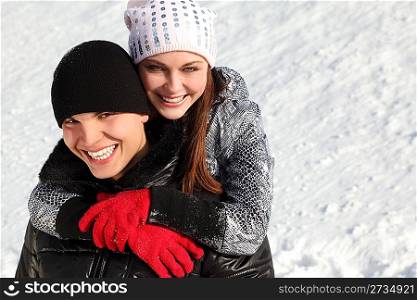 portrait of young man and girl smiling and looking at camera, girl embracing man from back, winter day