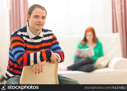 Portrait of young man and girlfriend reading in background