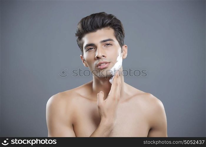Portrait of young man applying shaving cream