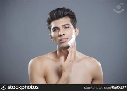 Portrait of young man applying shaving cream