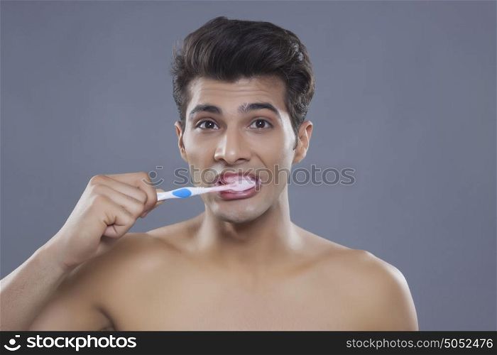 Portrait of young man brushing teeth