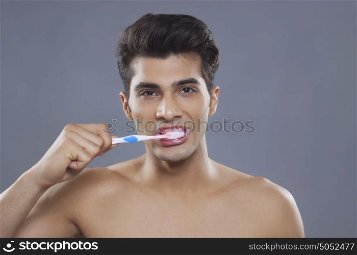 Portrait of young man brushing teeth